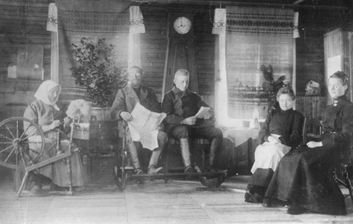 Valokuvassa perhe istuu tuvassa